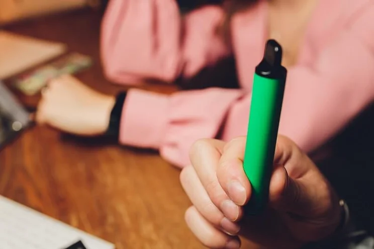 Person holding a green disposable vape