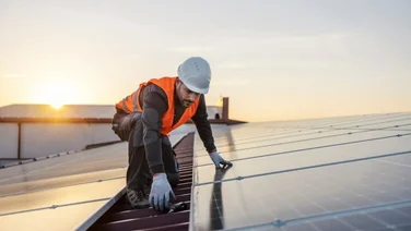 man installing solar panels on a roof