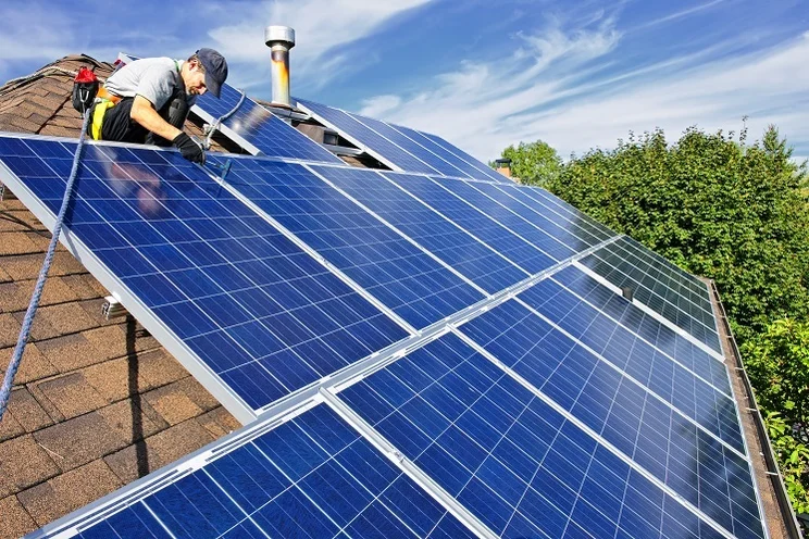 a man installs solar panels on a roof