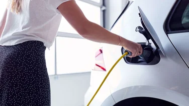woman plugging charger into electric vehicle
