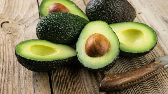 Avocados sliced in two on a wooden table