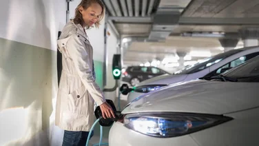 Young woman charging an electric vehicle in an underground garage equiped with e-car charger