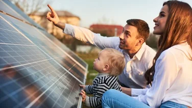 man, woman and child look at solar panels