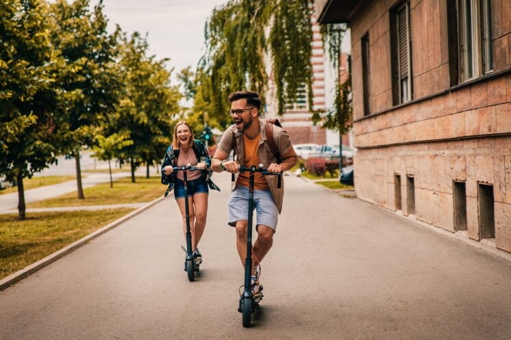 man and woman ride on electric scooters