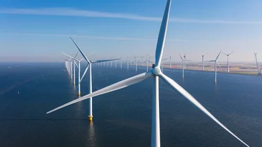 Close up of an offshore wind turbine with other turbines in the distance