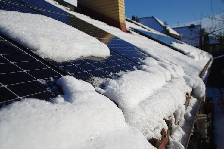Solar panels covered by snow on the home roof on a sunny winter's day