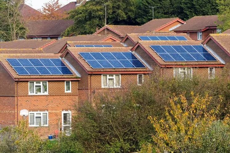 A row of three brown houses with solar panels
