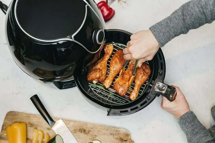 man opening taking roast chicken drumsticks out of air fryer