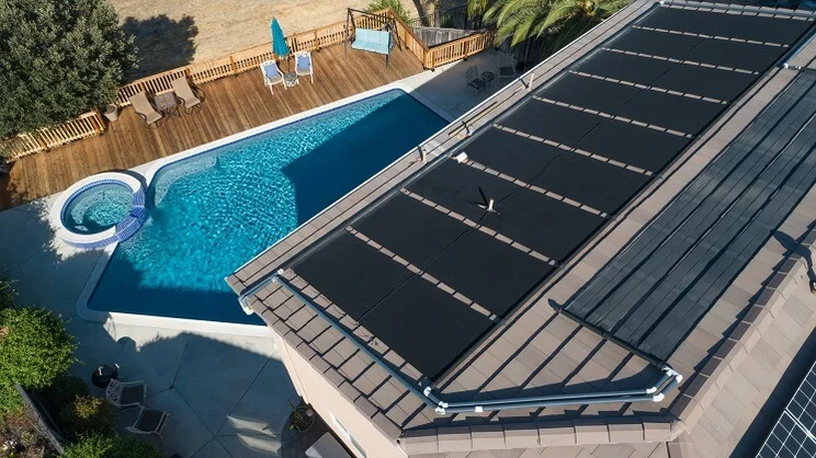 View of a house from above with solar panels on the roof and swimming pool in the garden