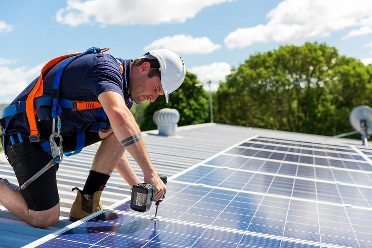 Installer fitting solar panels onto roof