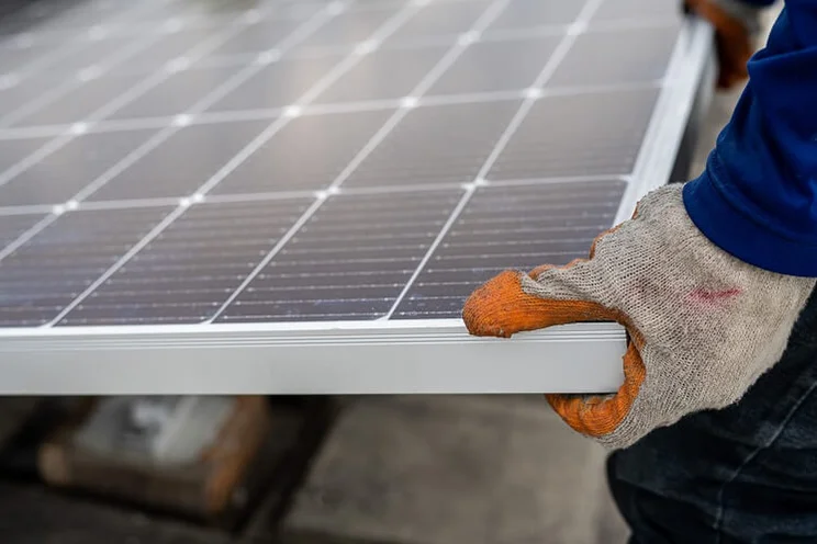 Close up shot of someone wearing a glove and carrying a solar panel