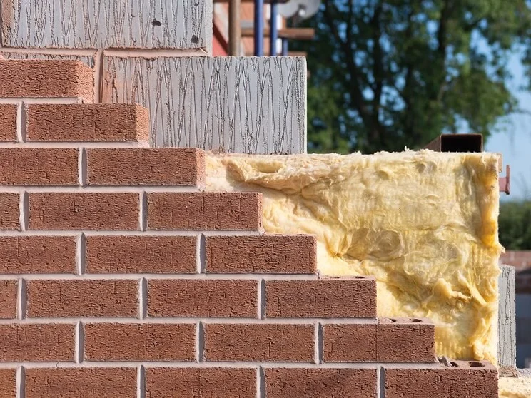 Cavity wall insulation showing behind a red brick wall