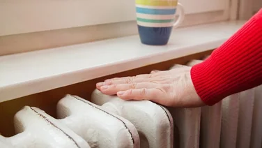 Person touches radiator to keep warm