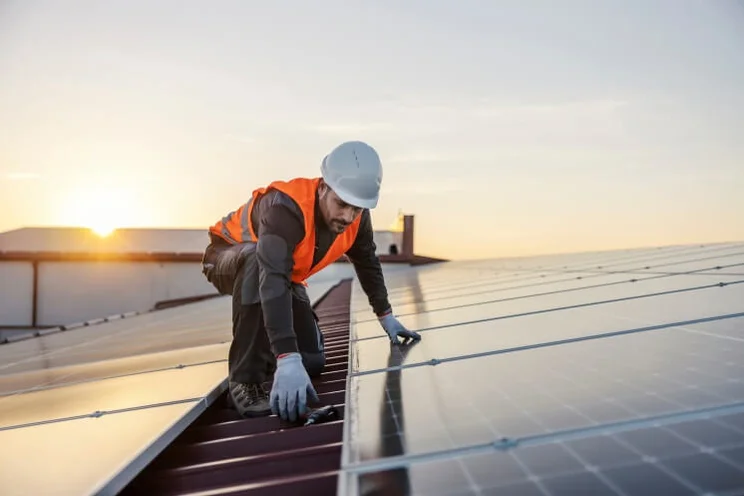man installing solar panels on a roof