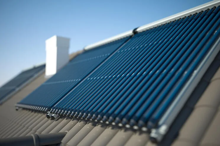 A close up of two solar thermal panels on a roof with grey slates underneath