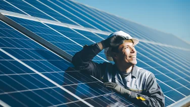 solar panel installer next to array of solar panels