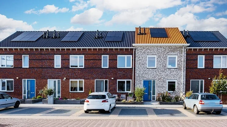 row of terraced houses with solar panels on roof and cars parked in driveways