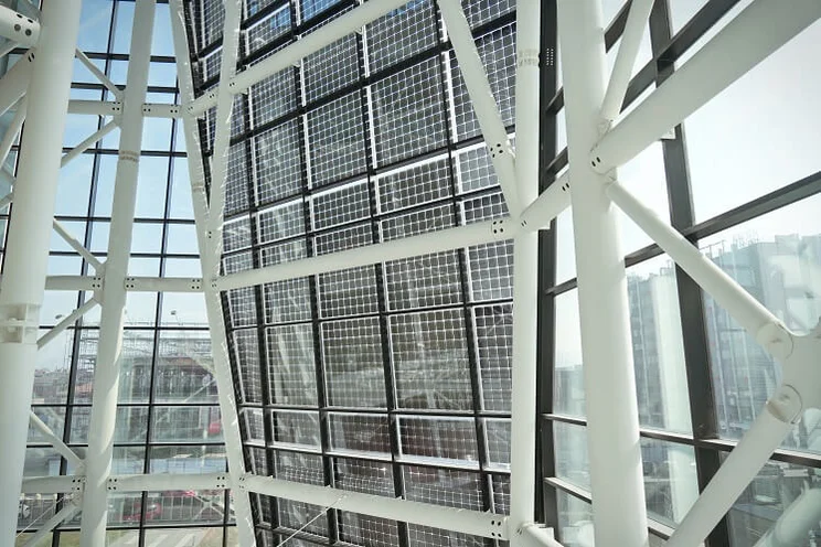 wall of transparent solar panels seen from the inside of a building with glass walls