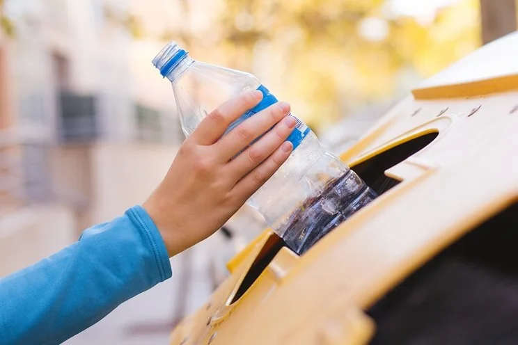 Woman putting plastic bottle in recycling bin