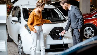 Sales manager with client near electric car at a car dealership