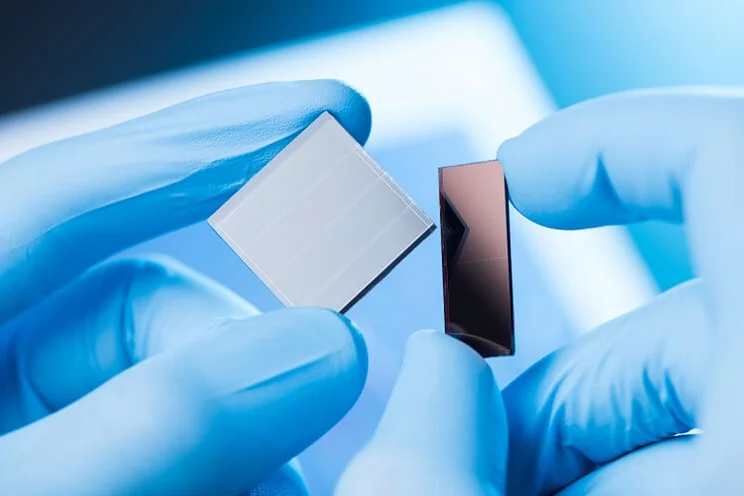 close up of solar cells in a lab bein held by gloved hands