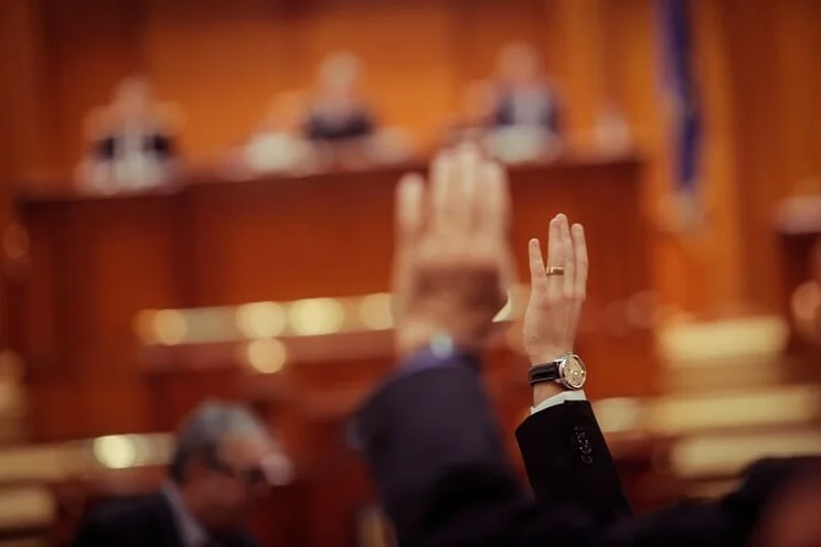Blurred image of MPs raising hand to vote in Parliament