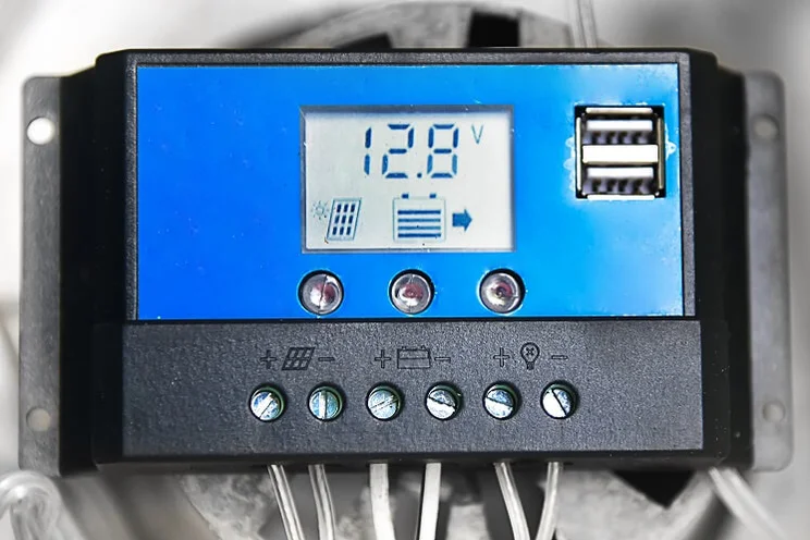 A blue and black solar charge controller showing figures on the digital screen