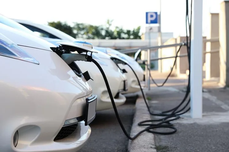 White electric cars charging in a row