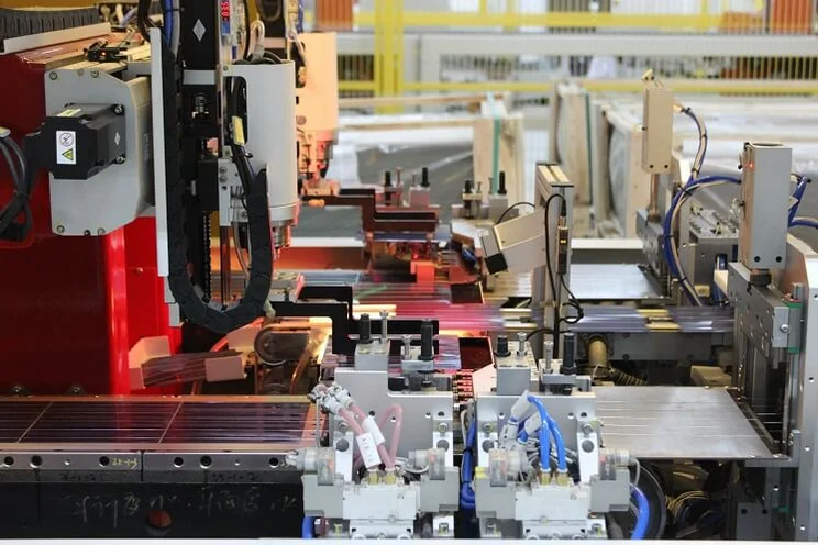 solar panels on tables in factory with machine arms working on them