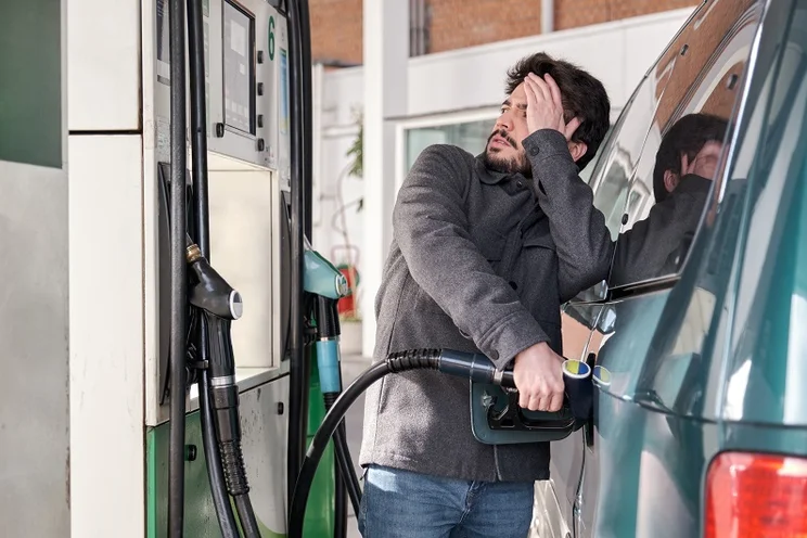 Man-looking-at-petrol-prices-and-grimacing