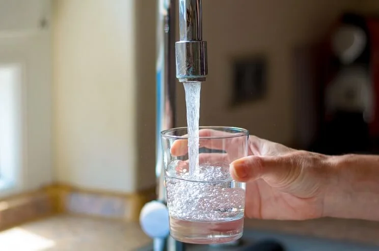 woman's hand filling up glass with water from tap