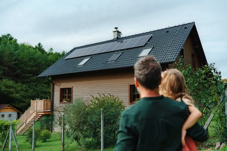 father and daughter looking at solar panel system on the roof of their home