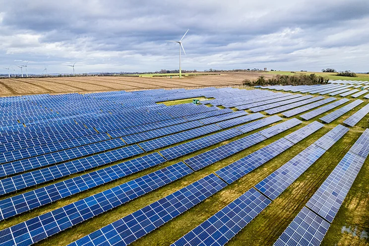 Solar farm in the UK, with wind turbines in the background