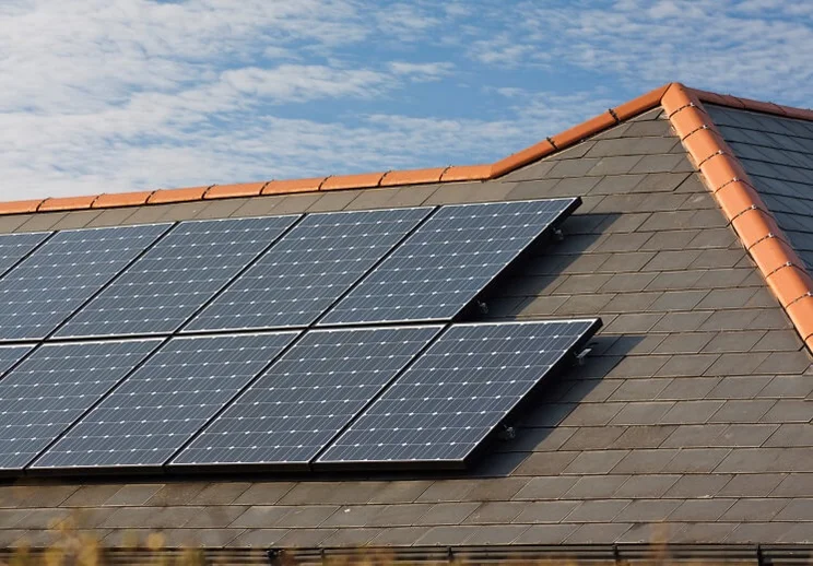 Solar panels on a slate roof under a blue sky