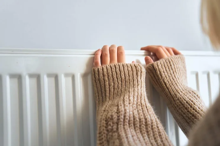 Person resting their fingertips on top of a radiator