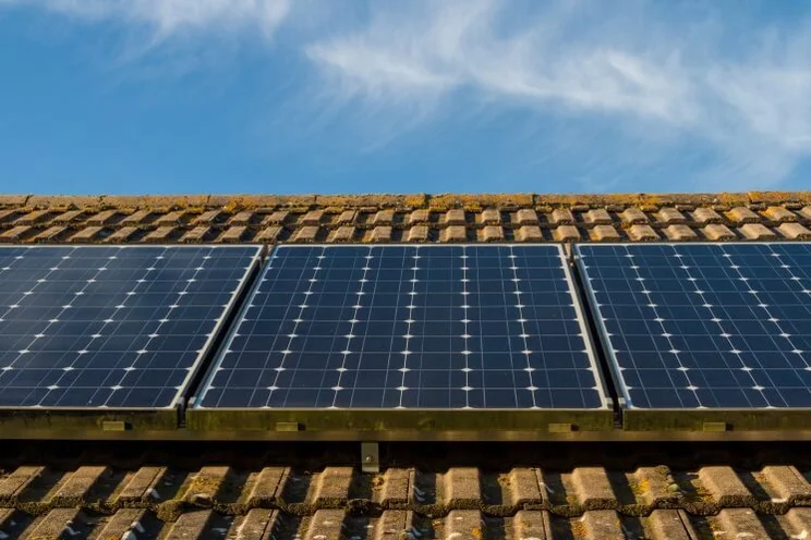 solar panels on a brown roof, under a blue sky with clouds