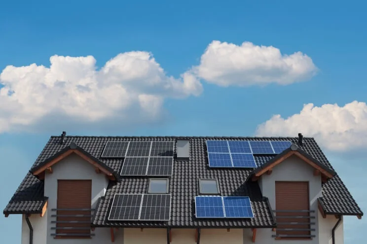monocrystalline and polycrystalline solar panels on a house against a blue sky with clouds
