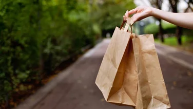 two brown paper bags in hand