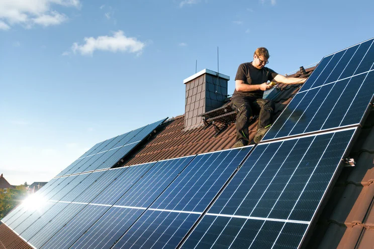 Man installing solar panels on a roof