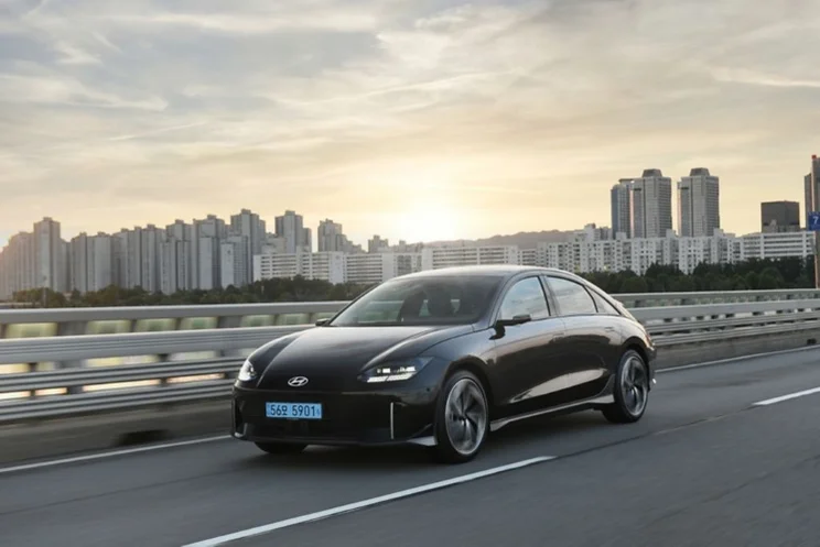 a hyundai ioniq 6 on a road against a skyline and a sunrise