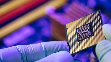 Semiconductor chip being held by a person wearing gloves, from their point of view