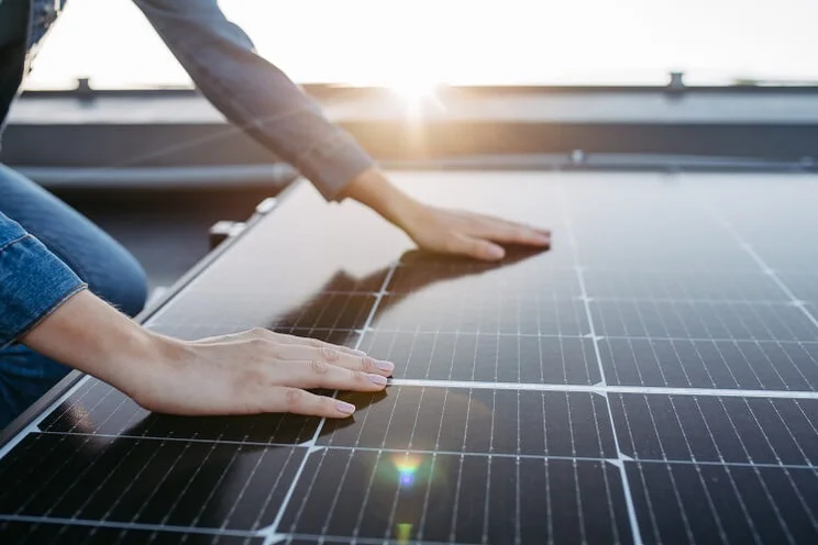 Someone putting their hands on the surface of a monocrystalline solar panels with black solar cells