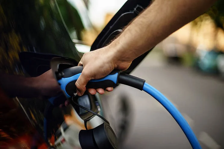 Person using EV charger connected to car