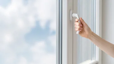 Woman with hand on handle of double glazing window