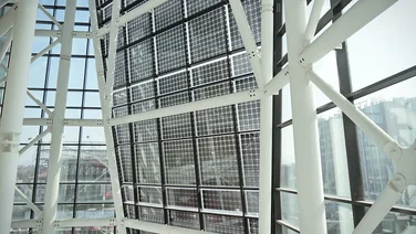 wall of transparent solar panels seen from the inside of a building with glass walls