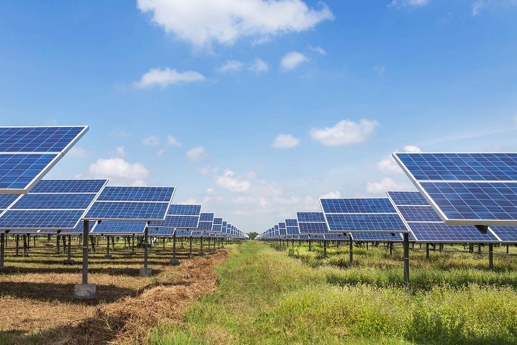 multiple solar panels in a grassy field with a path in the middle