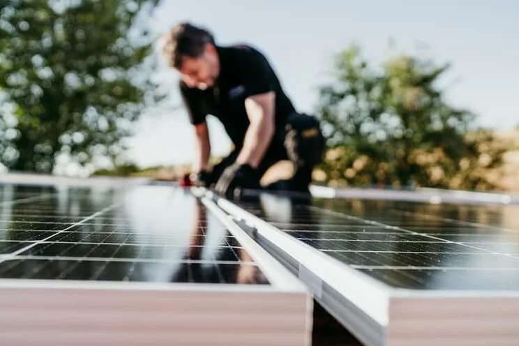 Someone on a roof fixing solar panels in place