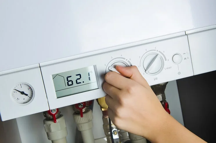 woman adjusting temperature on boiler