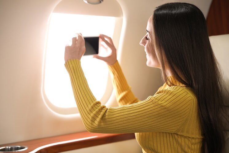 woman taking photo out of plane window