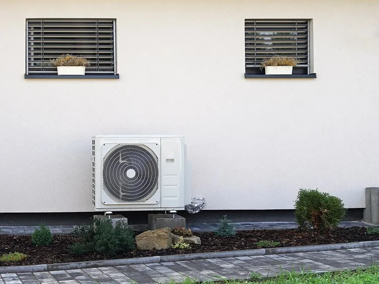 heat pump unit outside house, underneath windows
